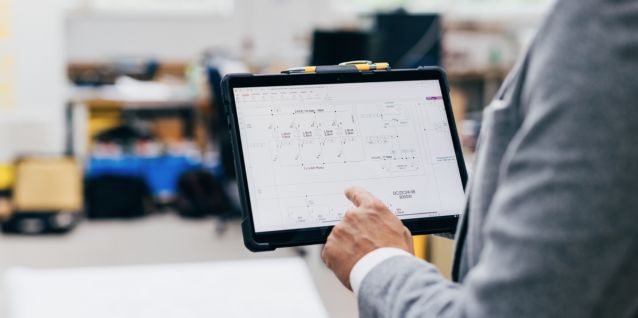 Mitarbeiter bedient Monitoring System auf Tablet